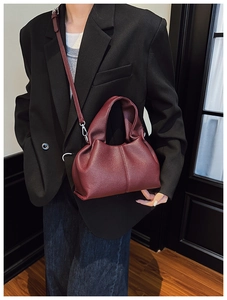 Détail du sac seau bordeaux grainé avec des plis élégants et des ferrures en métal argenté