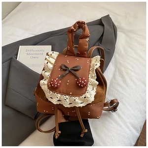 Détail d'un mini sac à dos floral avec dentelle blanche et pendentifs cerises mignons