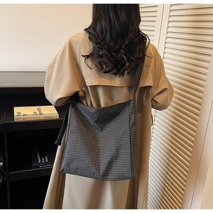 Detail of black and white checkered canvas tote bag with long shoulder strap in daily use