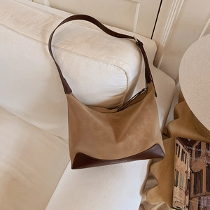 Detail of vintage patchwork faux leather shoulder bag with adjustable strap on white sofa