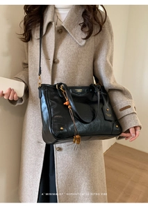 Close-up of black retro tote bag with gold hardware and wood bead tassel detail