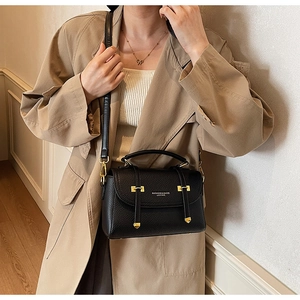 Detailed view of black litchi pattern leather satchel with golden buckles and shoulder strap