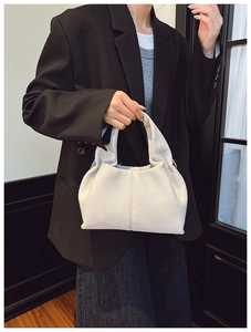 Détail du sac seau en cuir PU blanc à texture litchi avec une élégante poignée plissée