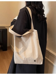 Grand sac cabas beige imperméable porté à l'épaule dans un intérieur urbain chic