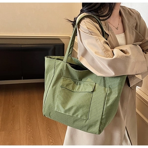 Detail of green plaid canvas tote bag with long straps and functional front pocket flap