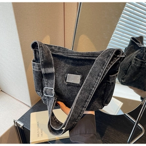 Détail du sac fourre-tout en denim noir délavé avec plaque métal et bandoulière large