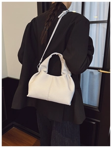 Side view of white lychee leather bucket bag with top handle and slim shoulder strap