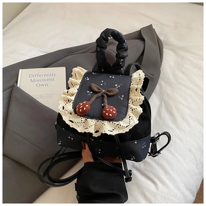 Détail du mini sac à dos bleu marine avec dentelle et cerises sur blazer gris
