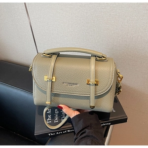 Detail of light olive green pebbled leather satchel with gold hardware and top handle