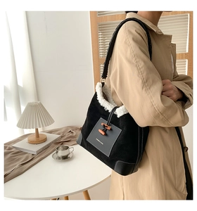 Detailed shot of black suede shoulder bag with white faux fur trim and toggle closure