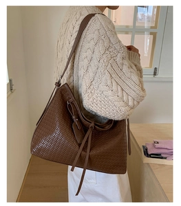 Gros plan détaillé du sac à bandoulière marron foncé avec texture tressée et pompon