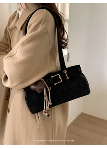 Close-up of black suede shoulder bag with gold hardware and heart-shaped tassel detail