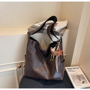 Detail of deep brown large tote bag with soft leather texture and plush bear charm