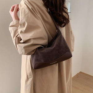 Detail of a large vintage brown suede hobo bag styled with a khaki trench coat