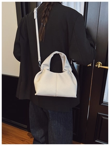 Gros plan sur la texture du cuir blanc grainé d'un sac seau vintage porté en bandoulière