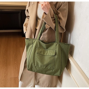 Detail of green plaid oxford tote bag featuring a front pocket and long handles