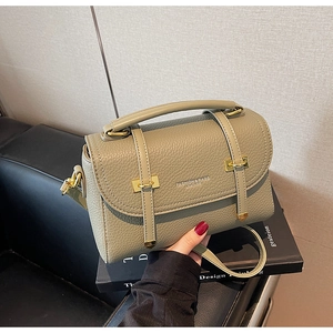 Detail of sage green lychee grain leather bag with elegant gold clasp and handle