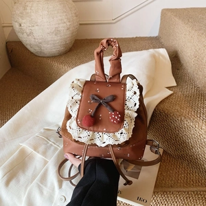 Gros plan d'un mini sac à dos vintage marron avec fleurs et finitions en dentelle