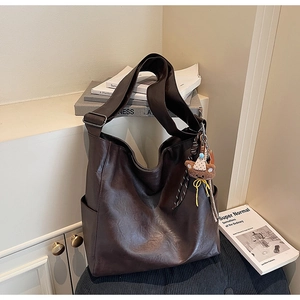Detail of dark brown tote bag with pebble leather texture and cute bear pendant charm