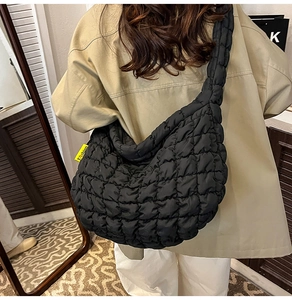Détail du sac croissant matelassé noir avec étiquette Fashion jaune porté à l'épaule