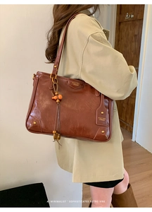Detail of vintage brown leather tote bag with gold rivets and beaded tassel charm