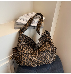 Detail view of leopard print canvas bag with multiple pockets and adjustable black strap