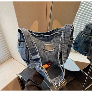 Détail du sac en jean vintage avec plaque logo métallique et coutures à bords effilochés