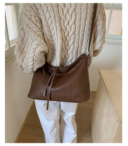 Détail du sac à main tissé marron foncé avec bandoulière et étiquette décorative