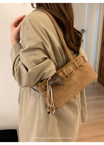 Detail of a brown suede shoulder bag with heart pendant and metallic strap buckle