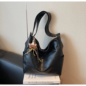 Detail of black large capacity hobo bag with wide strap and cute bear plush charm