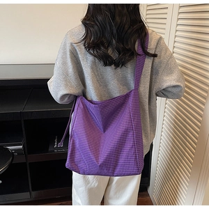 Detailed back view of a large purple plaid oxford fabric tote bag worn by a model