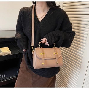 Detail of vintage brown lychee grain leather bag with gold buckle on a model