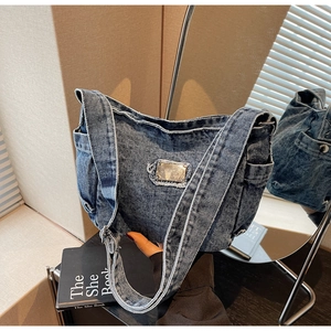 Détail d'un sac bandoulière en jean vintage avec poches latérales et bandoulière réglable
