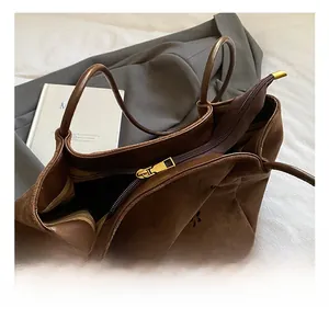 Detailed macro view of the premium golden zipper hardware on a brown suede tote bag