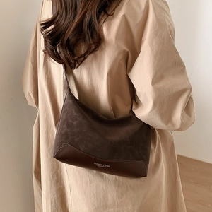 Detail of dark brown Hobo bag with suede and leather textures worn by a model
