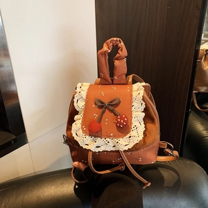 Détail d'un mini sac à dos vintage avec dentelle, imprimé floral et pendentif cerise