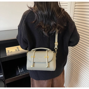 Green textured crossbody bag with metal buckle shown on model in home setting