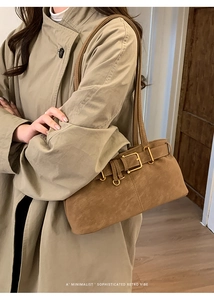 Close-up of retro brown suede shoulder bag with gold buckle and leather strap details