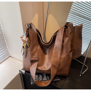 Detail view of brown faux leather tote bag with soft texture and cute bear pendant