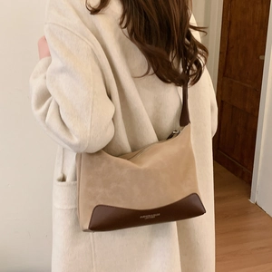 Close-up of beige suede hobo bag with brown leather base on a white wool coat