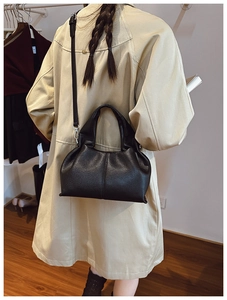 Détail d'un sac seau en cuir grainé noir montrant la texture et les ferrures argentées