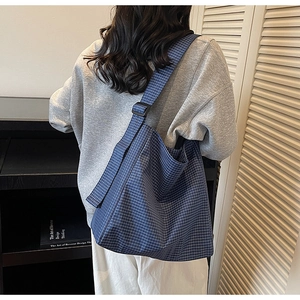 Detail of adjustable shoulder strap and plastic buckle on blue plaid oxford tote bag