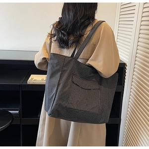 Detailed back view of a grey checkered tote bag worn by a model in a modern room