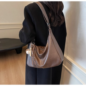 Brown leather Hobo bag with white contrast stitching and baseball charm on a shoulder