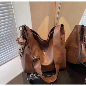 Detail of dark brown tote bag with leather texture and cute plush bear charm