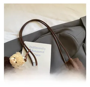 Detail of brown suede tote with hollow floral patterns and a cute plush bear charm