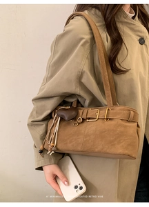 Detail of light brown suede shoulder bag with heart pendant and metallic buckle detail