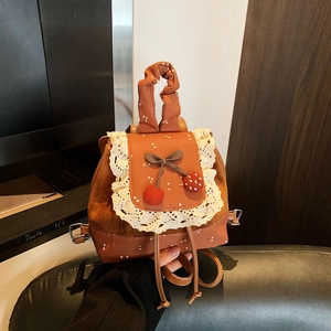 Détail d'un mini sac à dos vintage avec bordure en dentelle et décor cerise et nœud