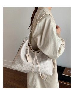 Détail du sac fourre-tout tressé crème avec cordon latéral et forme hobo décontractée