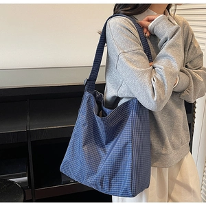 Detailed close-up of blue plaid Oxford fabric and reinforced stitching on tote bag
